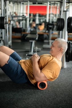 Adam spor salonunda köpüklü rulo ile kas düzeltme egzersizleri yapıyor.