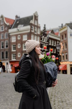 Amsterdam 'da Hollanda Evlerinin önünde lale tutan genç kadın