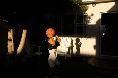Genç melez Afrikalı çocuk, maçtan sonra evde basketbol oynuyor.