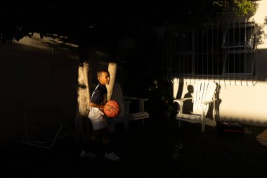 Genç melez Afrikalı çocuk, maçtan sonra evde basketbol oynuyor.