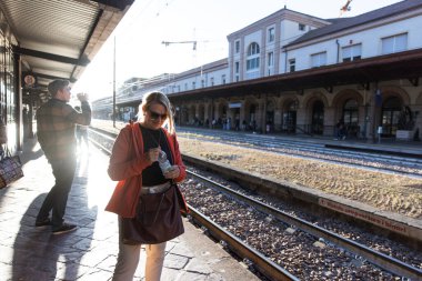 Güneş ışığında Bozen tren istasyonunda su içen bir kadın.