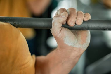 Salonda tebeşirle halteri tutan güçlü bir elin yakın çekimi.