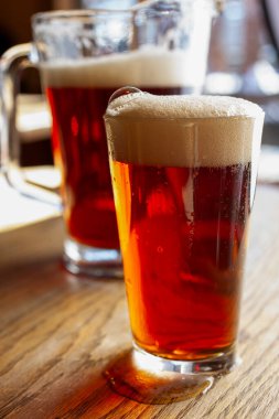 Köpüklü kafası ve sürahisi olan bira bardağının yakın görüntüsü