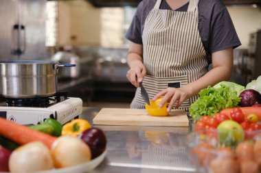 Mutfakta sebze doğrayan genç bir kadın..