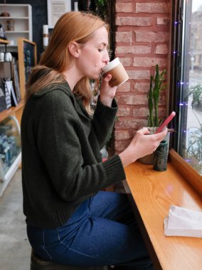 Uzun saçlı, cappuccino içen ve kahvecide kayan bir kadın.