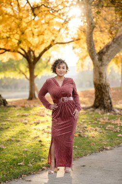 Sonbahar ağaçlarıyla parkta duran bir kadın.