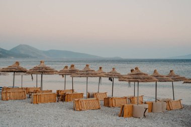 Arnavutluk 'un Qeparo Plajı' ndaki Plaj Sandalyeleri ve Hasır Güneş Gölgeleri
