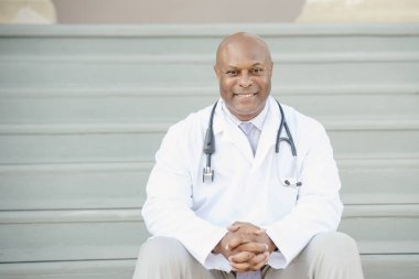 Gülümseyen doktor sıcak ve misafirperver bir tavırla merdivenlerde oturuyor.