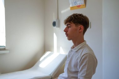 Klinikte aşı bekleyen genç bir adam.