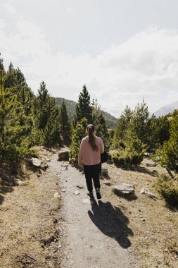 Güneşli orman patikalarında yürüyüş yapan bir kadın
