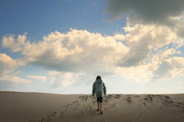 Genç kızın arkasında yüksek kum tepelerine tırmanıyor Dış Kıyılar Kuzey Arabası