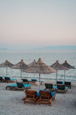 Arnavutluk 'un Qeparo Plajı' ndaki Plaj Sandalyeleri ve Hasır Güneş Gölgeleri