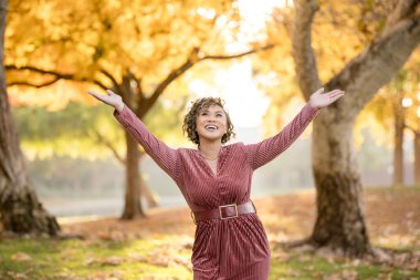 Sonbaharı altın yapraklarla kutlayan neşeli bir kadın.