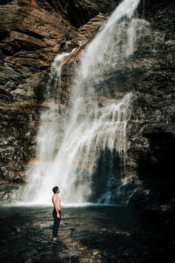 Adam gökkuşağıyla uzun şelaleye hayran.