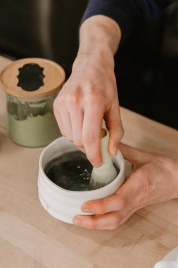 Ahşap bir kafe tezgahında seramik bir kasede elleri kibriti çırpıyor.