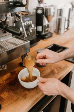 Barista beyaz bir kahve bardağına taze kahve dolduruyor.
