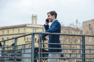 İş adamı parmaklıklara yaslanıyor ve cep telefonuyla konuşuyor