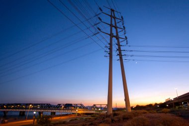 Akşam karanlığında yüksek voltajlı elektrik direklerini ve hatları