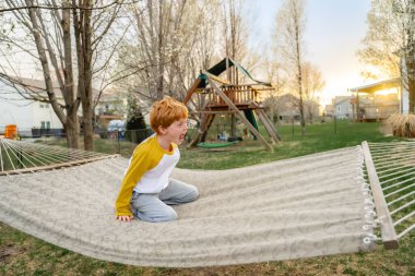 Baharda hamakta oynayan büyük gülümsemeli bir çocuk.