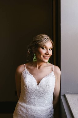 Sarı saçlı gelin, kamera karşısında gülümsüyor.