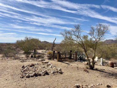 Tahta duvarları, kaya mezarları, kaktüsleri olan ıssız bir çöl mezarlığı.