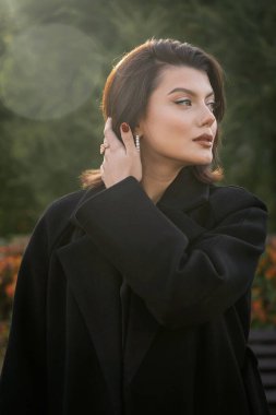 Güz parkında siyah ceketli güzel bir kadın.