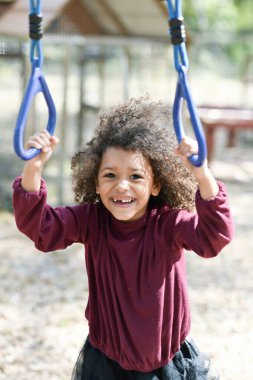 Gülümseyen çocuk açık hava setinde çocuk yüzüklerini tutuyor.