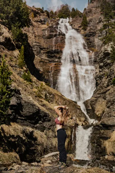 Dağlarda şelalenin yanında duran bir kadın
