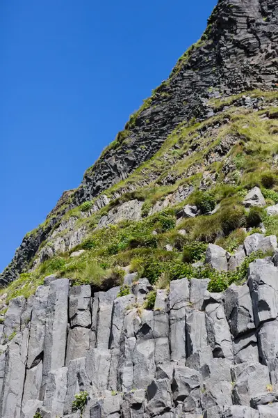 Yeşil bitki örtüsüyle kaplı sütun bazalt kayalıkları