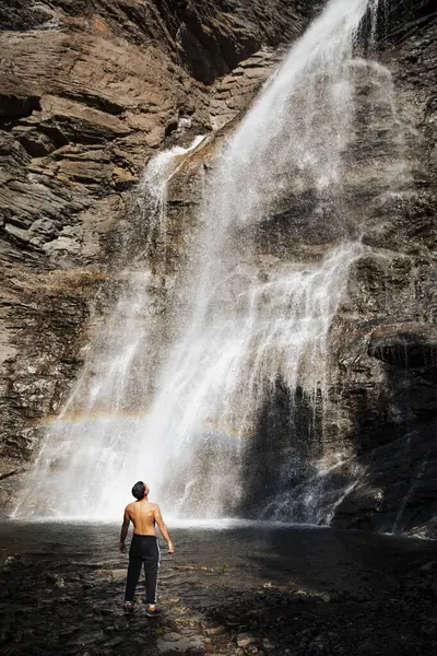 Adam gökkuşağıyla uzun şelaleye bakıyor.