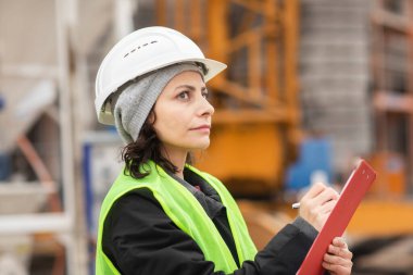 Dışarıda kaskla çalışan kadın teknisyen.