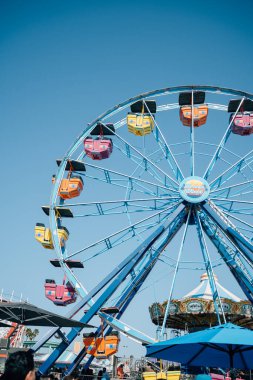 İnsanlar güzel güneşli bir günde sahil yolunda dönme dolaba biniyorlar.