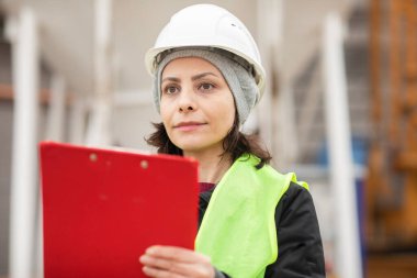 Dışarıda kaskla çalışan kadın teknisyen.