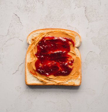 Üst manzara fıstık ezmesi ve reçel beyaz ekmek dilimine yayılmış..