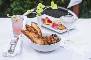 Cioppino ve salata beyaz masada, içkilerle birlikte.