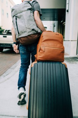 Gezgin, valiz ve sırt çantasıyla sokakta yürüyor.