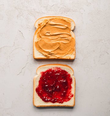 Üst manzara fıstık ezmesi ve reçel beyaz ekmek dilimlerine yayılmış..