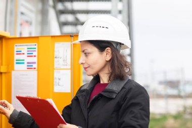 Dışarıda kaskla çalışan kadın teknisyen.