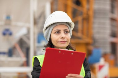 Dışarıda kaskla çalışan kadın teknisyen.