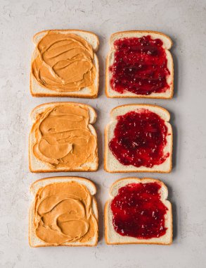 Üst manzara fıstık ezmesi ve reçel beyaz ekmek dilimlerine yayılmış..