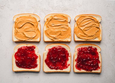 Üst manzara fıstık ezmesi ve reçel beyaz ekmek dilimlerine yayılmış..