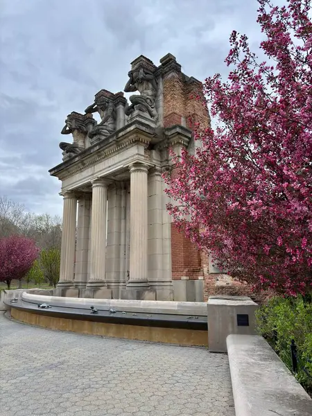 Çiçek açan pembe ağaçların heykel ve sütunlarıyla klasik taş kalıntıları.