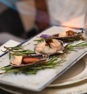 Beyaz tabakta biberiyeli taze çiğ deniz tarakları..