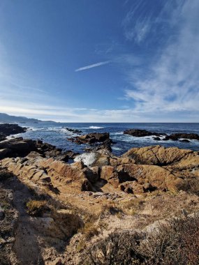Açık bir günde kayalık kıyı şeridi ve okyanus dalgalarıyla kıyı manzarası