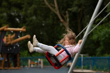 Çocuk parkında sallanan kızın yan görünüşü