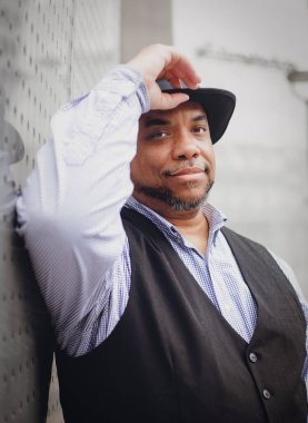 Siyah bir adam duvardaki bir şapkaya yansıyarak dokunur.