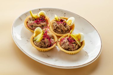 Kaz ciğeri, yumurta ve salatalık turşulu tartlar.