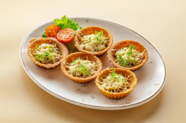 Peynirli tartlar ve tabakta otlar.