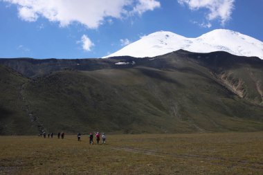 Bir grup turist vadi boyunca dağa doğru yürüyorlar..