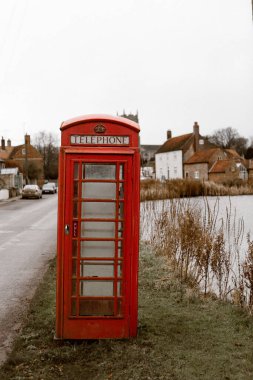 Great Massingham, İngiltere 'de göl kenarındaki klasik kırmızı telefon kulübesi.